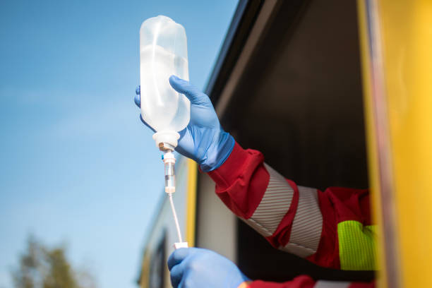 Close-up hand of paramedic holding IV drip in ambulance car of emergency medical service. Themes rescue, urgency and health care..