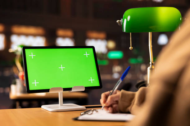 University scholar writes new project ideas next to green screen on tablet, gathering citations from reliable books and other sources at the library. Girl consulting the educational materials.