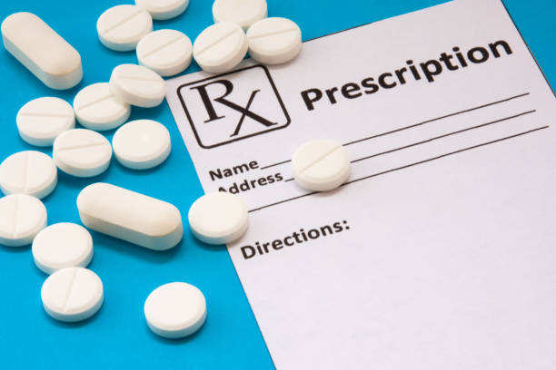 Clean recipe for prescription drug statement is near scattered white pills and tablets on a blue background. Pharmacological or medical concept photo to refer to prescription medicines for patients