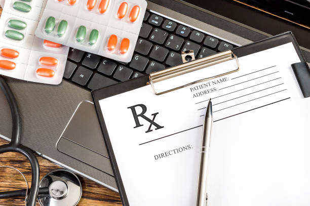 Prescription form with stethoscope and pills on the laptop keyboard.