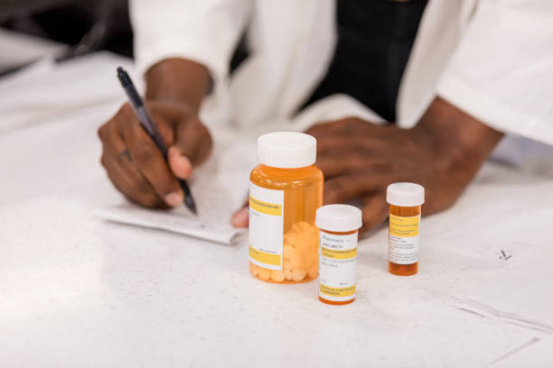 Healthcare professional fills out prescription.  Medication bottles sit nearby.